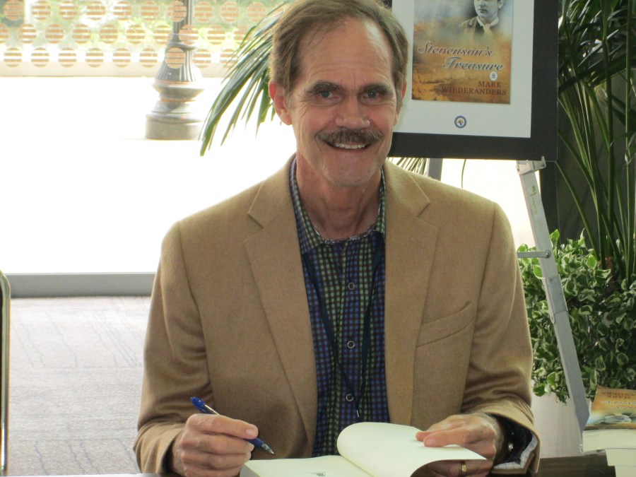 Mark W signing a book